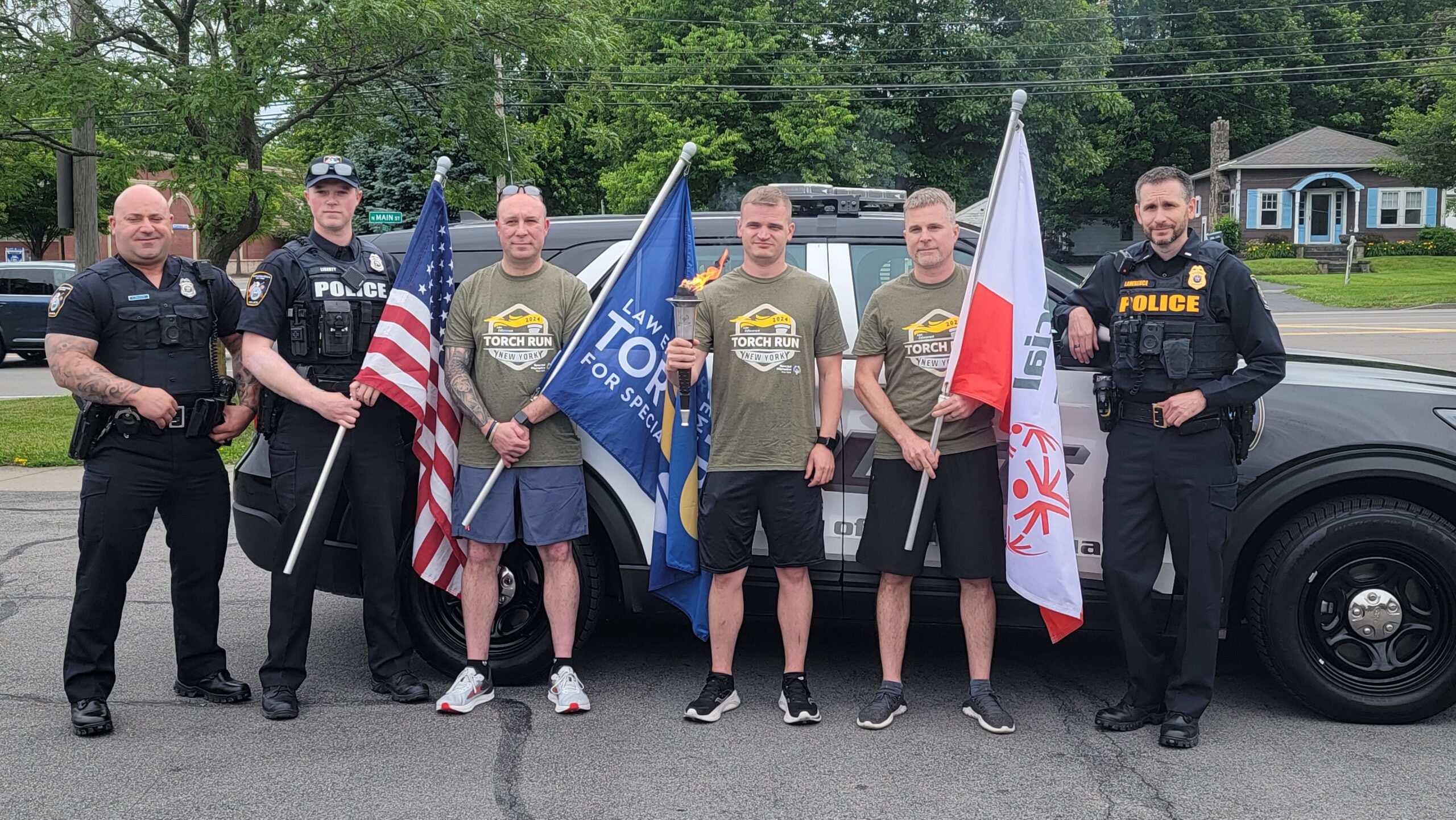 torch runners pose with the flame and flags