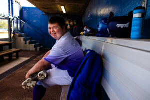 A Hot Shots player smiles in the dugout.